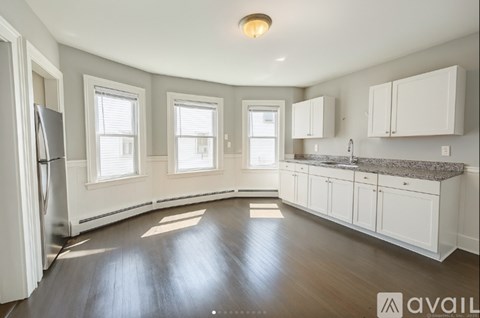 A kitchen with white cabinets and a refrigerator.