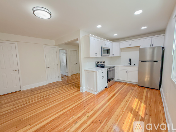 A kitchen with wooden floors and white cabinets.
