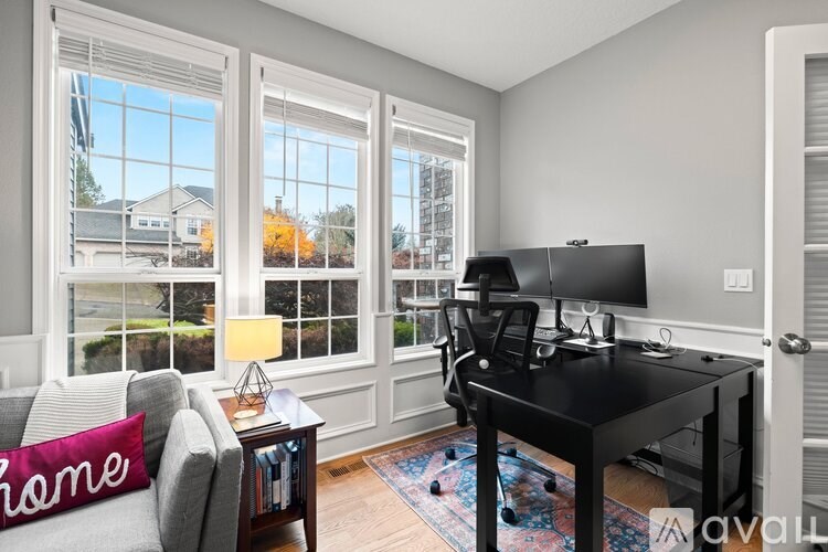 A room with a desk and a couch with a pillow that says home.