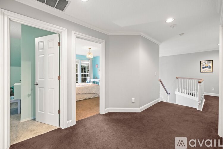 A room with a white door and a white crib in the corner.