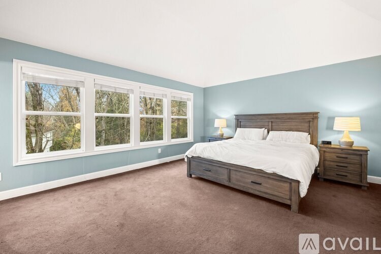 A bedroom with a large bed and two lamps.