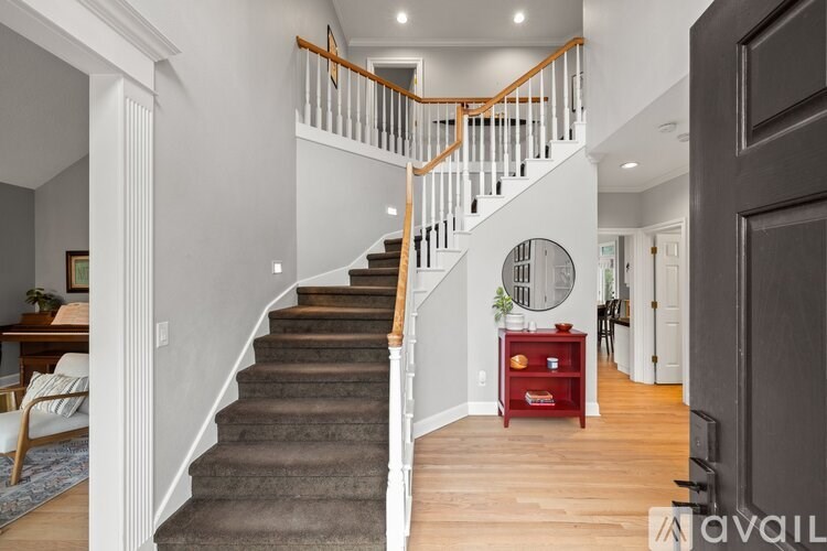 A staircase with a wooden handrail and a round mirror on the wall.