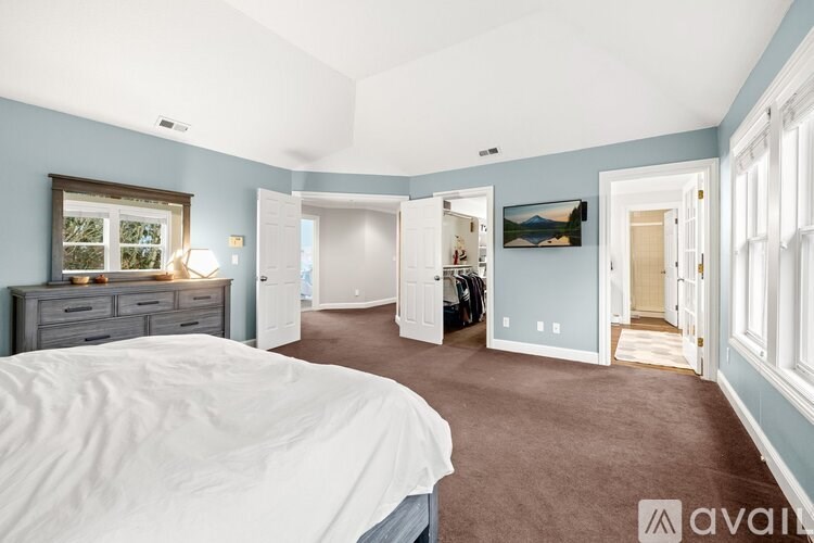 A bedroom with a bed, dresser, and a painting on the wall.