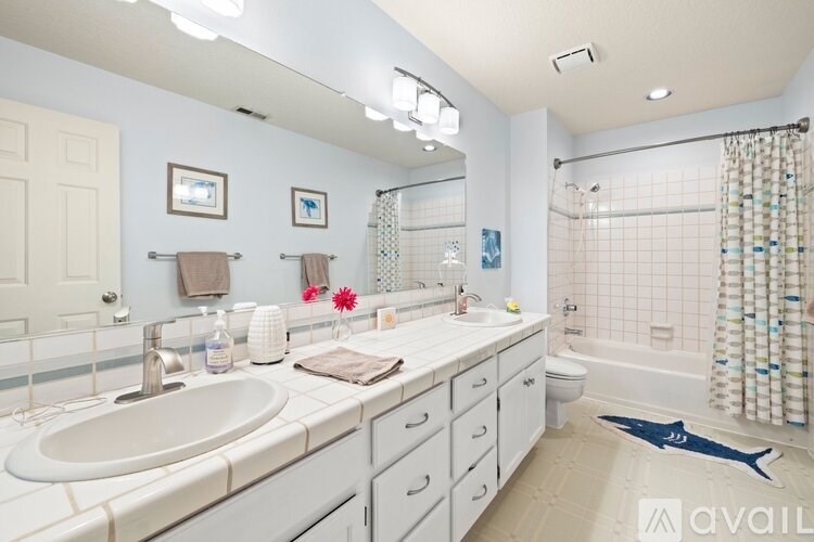 A bathroom with a sink, mirror, towel, and a shower curtain.
