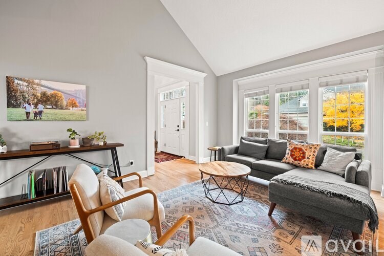A living room with a grey couch, a wooden chair, and a rug.