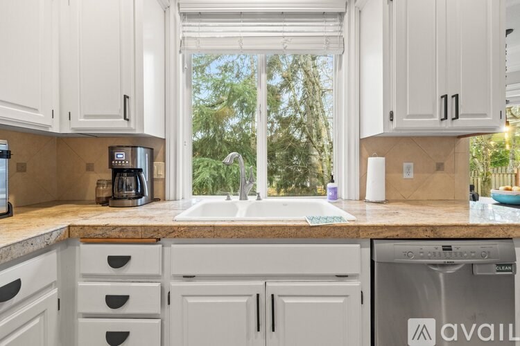 A kitchen with white cabinets and a marble countertop.