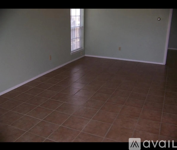 A room with brown tiled flooring and a window.