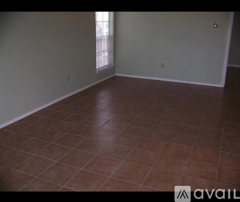 A room with brown tiled flooring and a window.