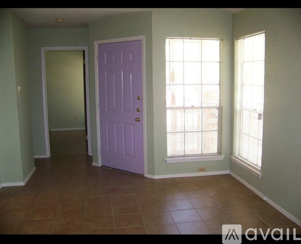 A room with a purple door and brown tile flooring.