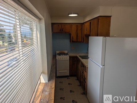 A kitchen with a white refrigerator and wooden cabinets.