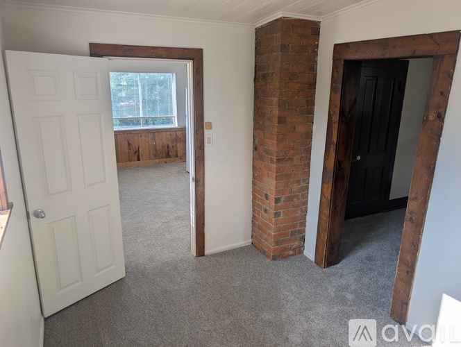 A room with a white door, a brick pillar, and a black door.