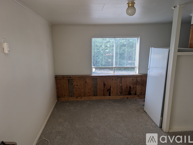 A room with a window and a wooden panel on the wall.