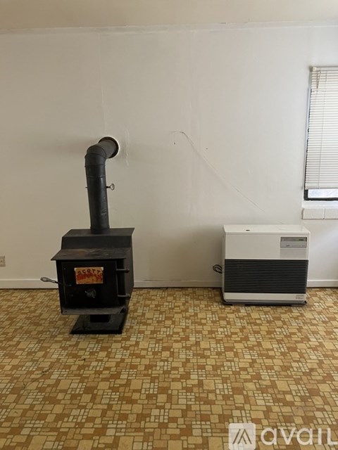 A wood stove is in a room with a tiled floor.