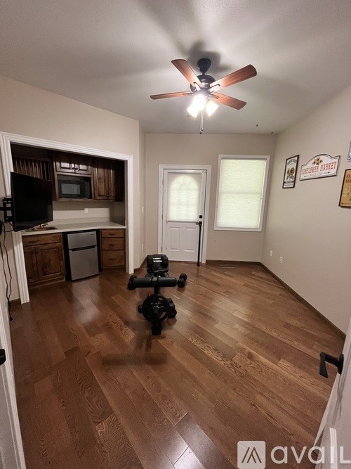 A room with a ceiling fan and wooden flooring.