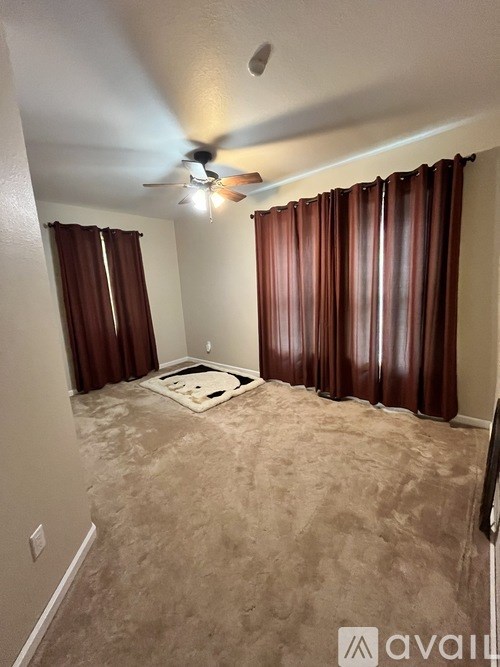 A room with a ceiling fan and carpeted floor.