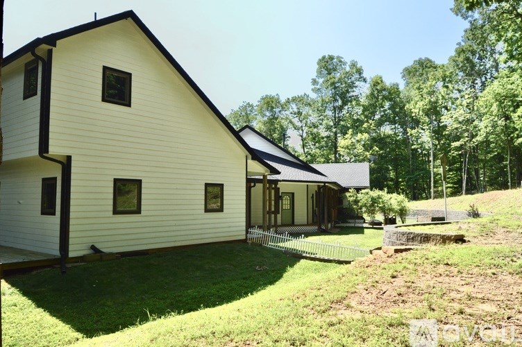 A white house with a black roof and a porch.