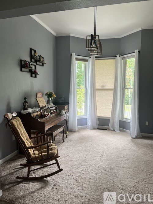 A room with a rocking chair and a desk with a lamp and some decorations.