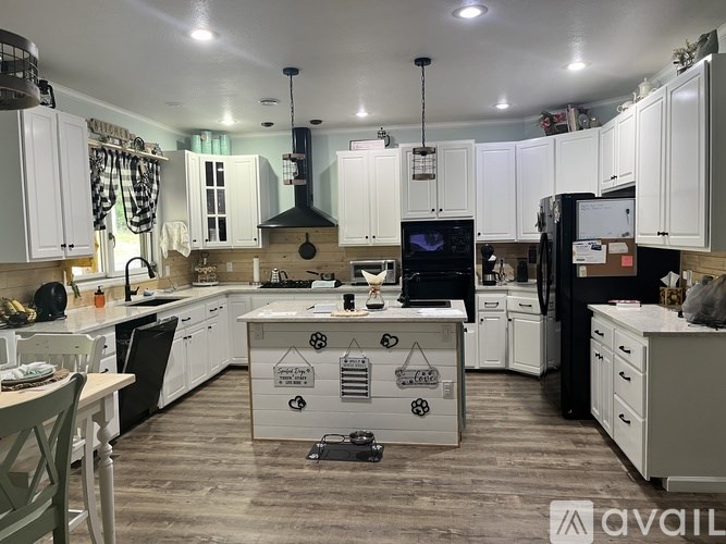 A kitchen with white cabinets and a wooden floor.