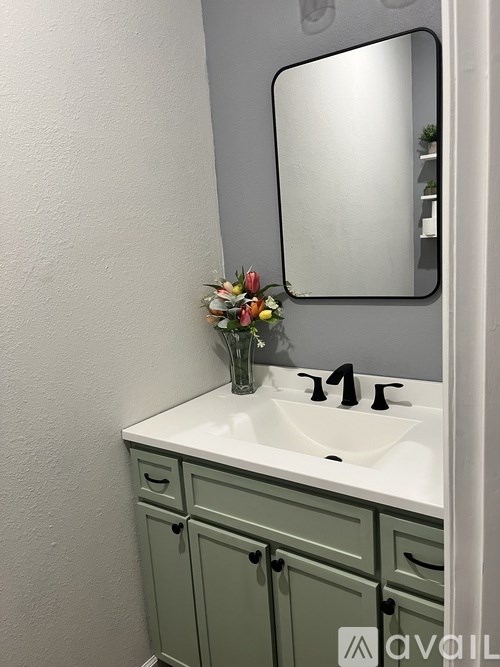 A bathroom with a white sink and green cupboards.