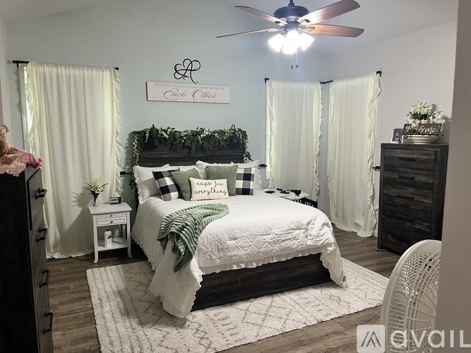 A bedroom with a bed, a dresser, and a ceiling fan.