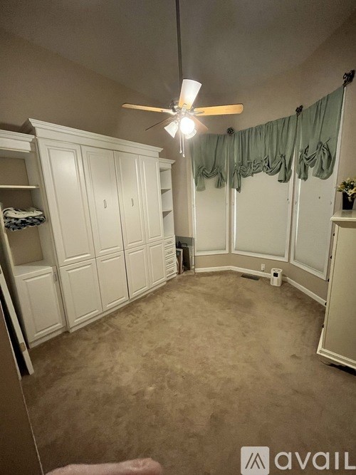 A room with a fan and a window with curtains.