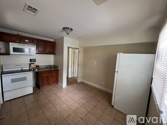 A kitchen with white appliances and brown cabinets.