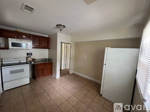 A kitchen with white appliances and brown cabinets.