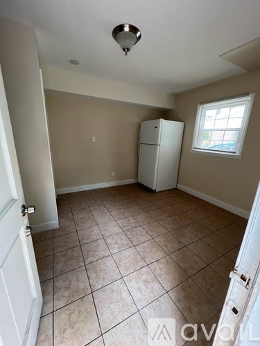 A room with a white refrigerator and a window.