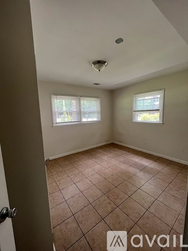 A room with tile flooring and two windows.
