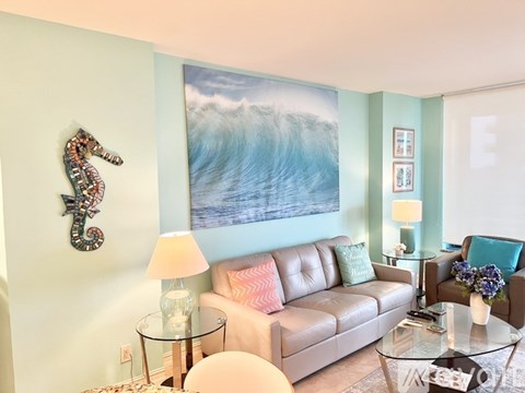A living room with a large painting of a wave on the wall.