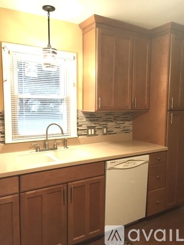 A kitchen with wooden cabinets and a white dishwasher.