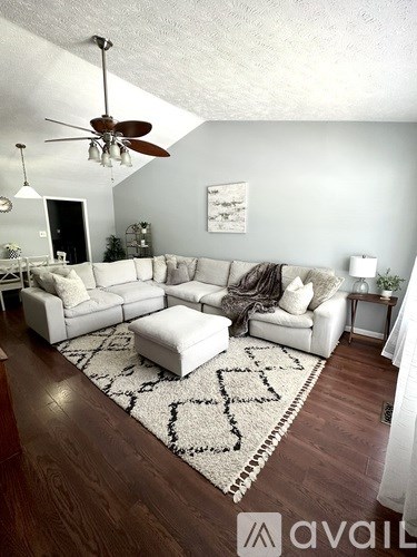 A living room with a white couch and a rug on the floor.