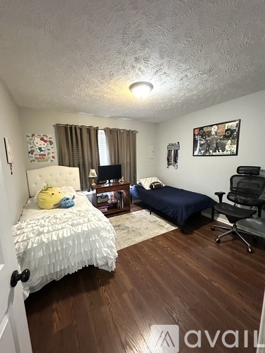 A bedroom with a bed, a chair, and a small bed in the corner.