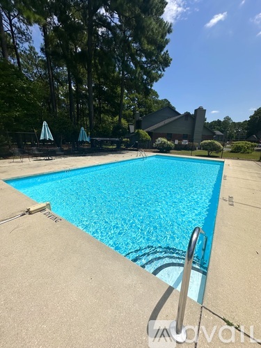 A swimming pool surrounded by trees and a house in the background.
