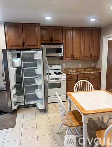 A kitchen with a table and chairs and a refrigerator with the door open.