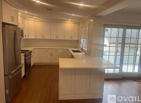 A kitchen with white cabinets and a wooden floor.