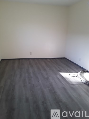 A room with wooden flooring and a white wall.