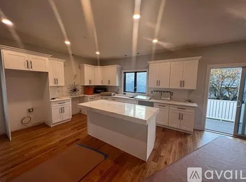 A modern kitchen with white cabinets and a wooden floor.