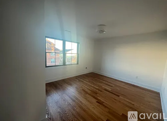 A room with wooden flooring and a window showing a view of a building.