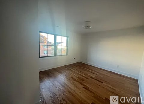 A room with wooden flooring and a window showing a view of a building.