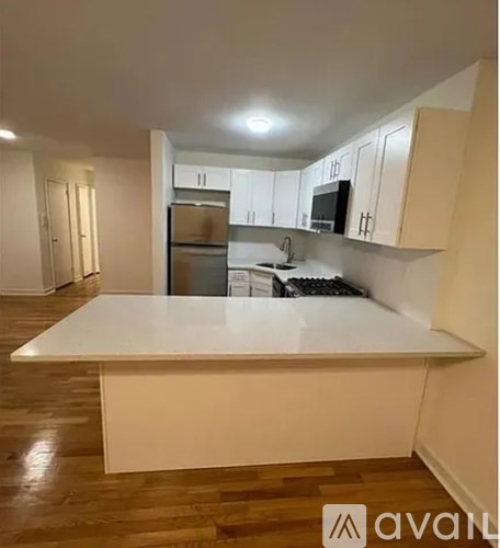 A kitchen with a white countertop and wooden floors.