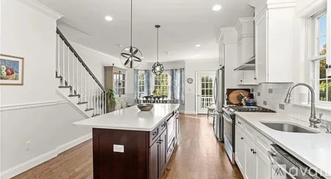 A modern kitchen with white cabinets and a wooden island.