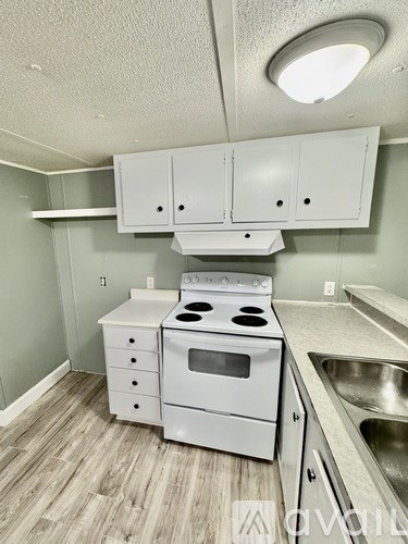 A kitchen with white appliances and wooden floors.