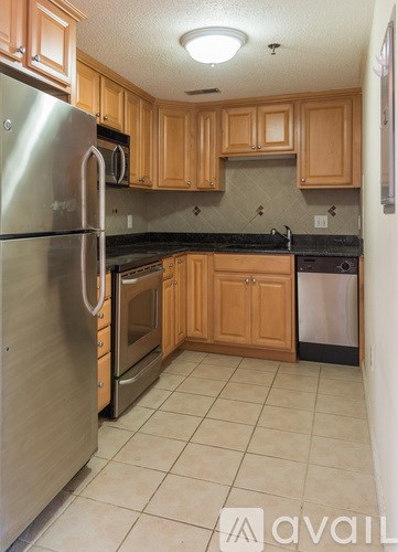 A kitchen with wooden cabinets and a stainless steel refrigerator.