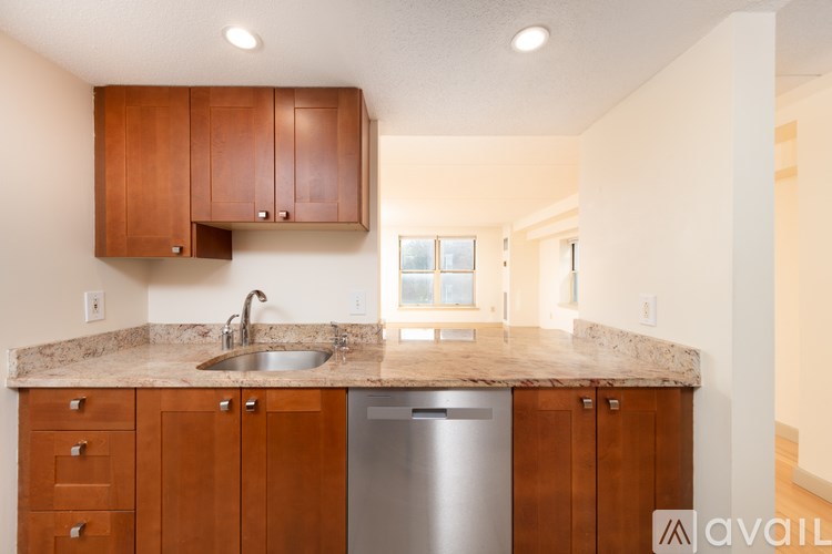 A kitchen with wooden cabinets and a stainless steel dishwasher.