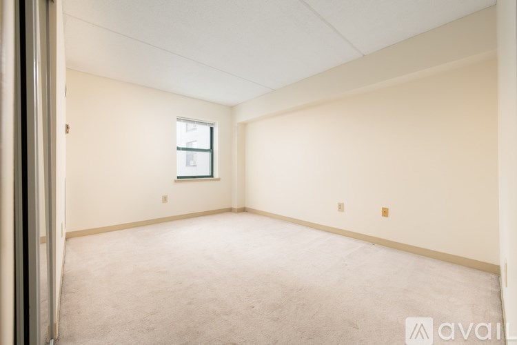 A spacious room with a window and carpeted floor.