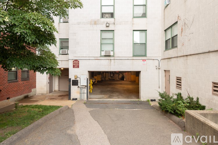 A building with a garage door open and a tree in front.
