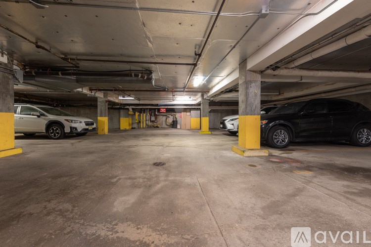 A parking garage with a white car and a black car parked in it.