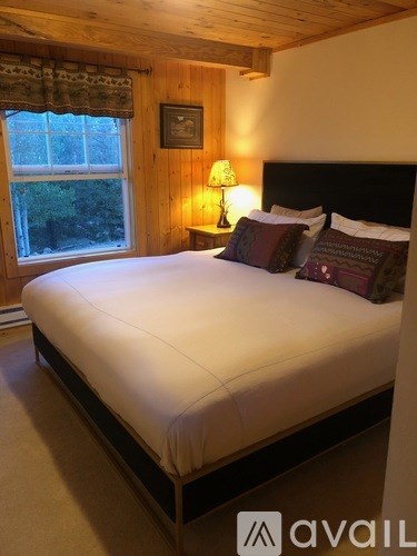 A bed with a white sheet and pillows in a room with wooden walls.