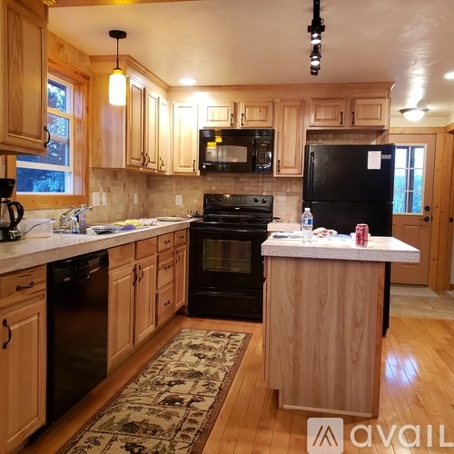 A kitchen with wooden cabinets and a black fridge.